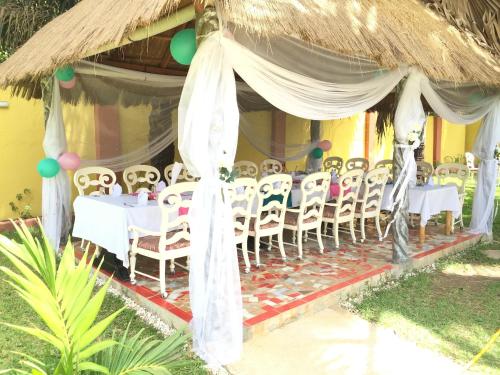 a group of tables and chairs under a thatch umbrella at Calabash Apartment-Hotel in Kotu