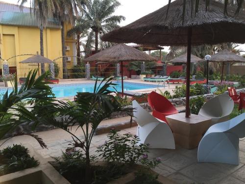 a resort with a pool with chairs and umbrellas at Calabash Apartment-Hotel in Kotu