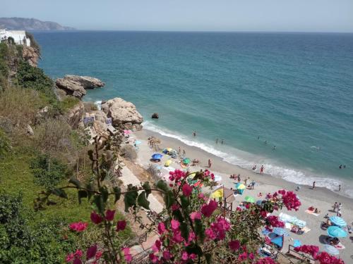 a beach with people and umbrellas and the ocean at Casa Eva - Adults Only in Nerja