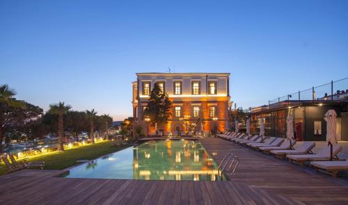 um hotel com piscina em frente a um edifício em Cunda Despot Evi em Cunda