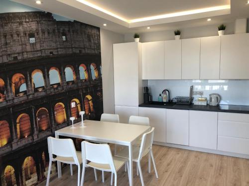 a kitchen with a white table and white chairs at Klimatyzowany Apartament ROMA z garażem podziemnym in Kielce