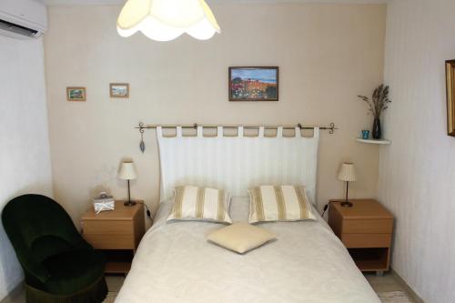 a bedroom with a bed and a green chair at Villa Nassalia in Lorgues