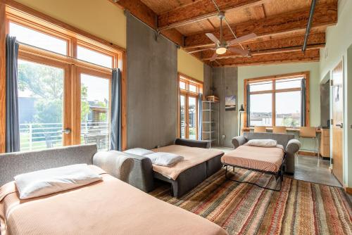 a bedroom with two beds and a couch and windows at The Crash Pad: An Uncommon Hostel in Chattanooga