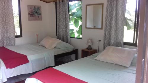 two beds in a room with two windows at Villa De Los Monos in Matapalo