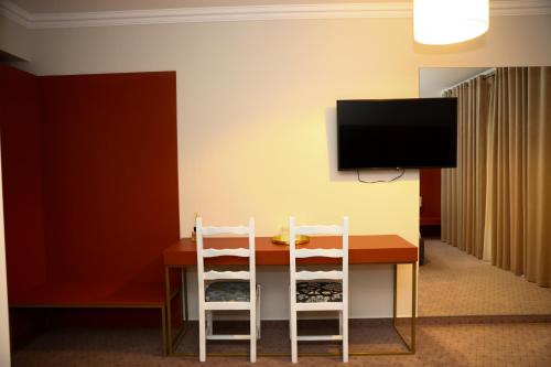 a dining room table with two chairs and a flat screen tv at Casa Budisteanu in Focşani