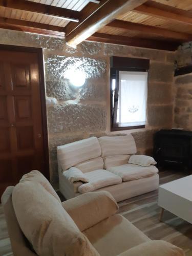 een woonkamer met een witte bank en een raam bij Casa en armenteira entera ideal para peregrinos precio segun numero de huéspedes , y grupos, in Pontevedra