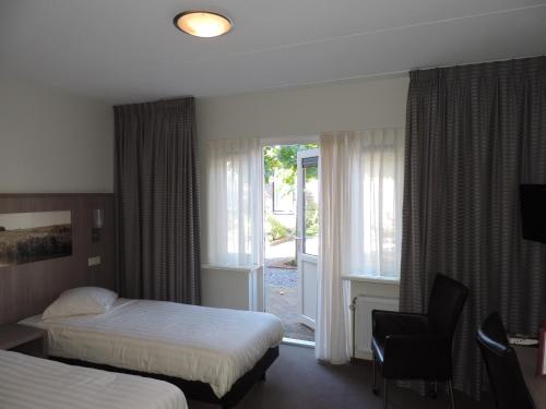 a hotel room with two beds and a window at Hotel Ekamper in Oosteinde