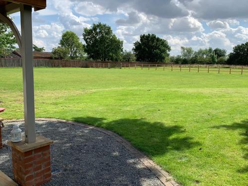 a large grassy field with a fence in the background at Field's Edge in Swinderby