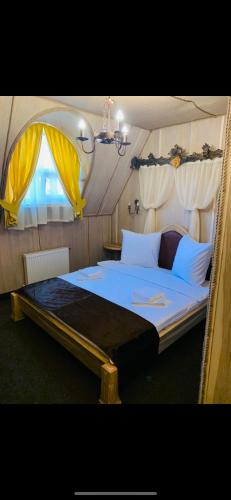 a bedroom with a large bed with yellow curtains at Готельно-ресторанний комплекс «Галицький замок» in Ternopilʼ