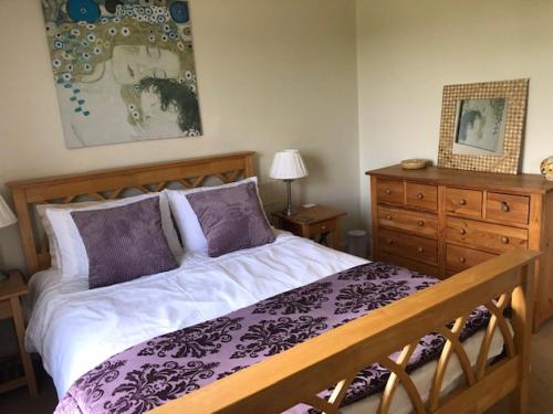 a bedroom with a bed and a dresser at Lynburn Country Retreat in Biggar