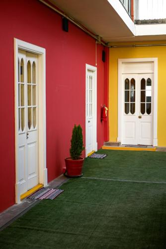 a red and yellow wall with two doors and a potted plant at Holidays Hostel Arequipa in Arequipa