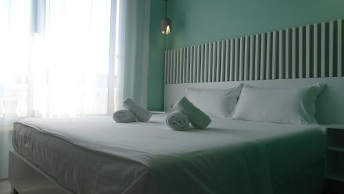 a bedroom with a large white bed with two pillows at Bistrica Hotel in Sarandë