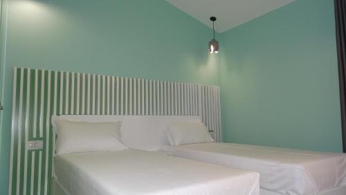 two beds with white sheets and pillows in a room at Bistrica Hotel in Sarandë