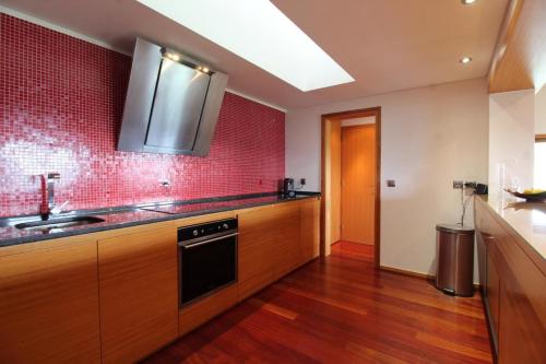 a kitchen with a sink and a red tile wall at Casa dos Cinco - Gerês in Terras de Bouro