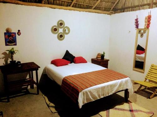 a bedroom with a bed with red pillows and a mirror at La Máxima & LGBT in Zipolite