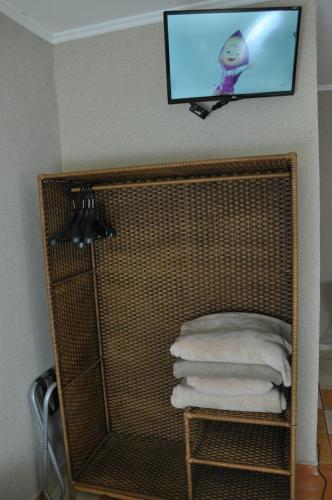einen TV an der Wand über einem Regal mit Handtüchern in der Unterkunft Pousada Beco da Lua in Olímpia