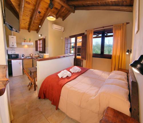 a bedroom with a large bed and a kitchen at Cabañas La Matera in Los Reartes