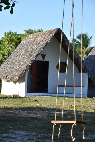 a house with a thatched roof and a swing at Pousada Velho Bateau in Atins