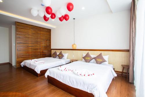 two beds in a room with red balloons on the wall at Luu Ngai Condotel Quy Nhon in Quy Nhon