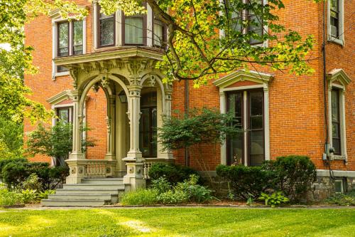 a red brick house with a porch and stairs at Rosemont Inn in Utica