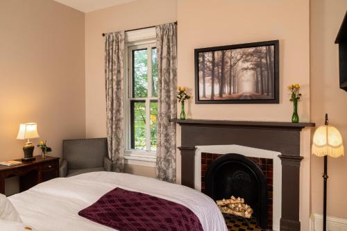 a bedroom with a fireplace and a bed and a window at Rosemont Inn in Utica