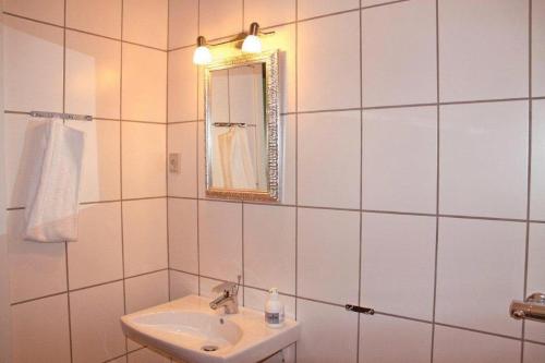 a white tiled bathroom with a sink and a mirror at Motel Højmølle Kro in Eskilstrup