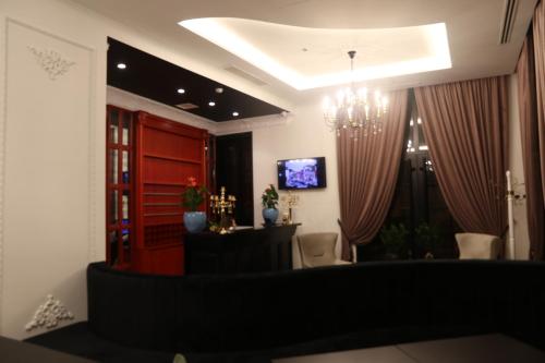 a living room with a chandelier and a table and a television at Hotel Kloest in Durrës