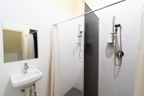 uma casa de banho branca com um lavatório e um chuveiro em myOZexp Aberdeen Lodge em Perth