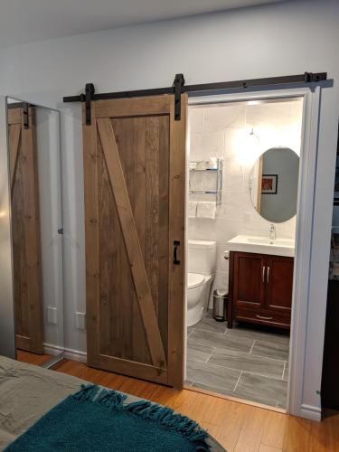 a bathroom with a sliding barn door with a sink and toilet at Oceanspray Hideaway in North Saanich