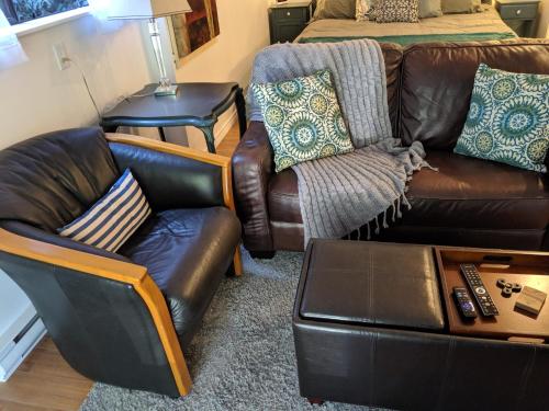 a living room with a leather couch and a chair at Oceanspray Hideaway in North Saanich