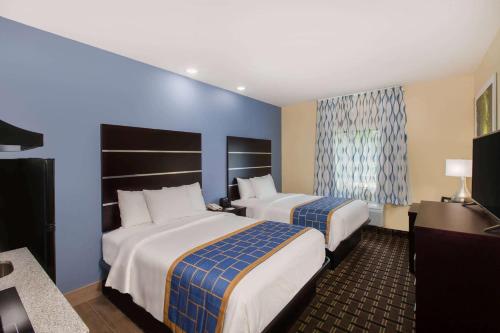 duas camas num quarto de hotel com paredes azuis em Days Inn by Wyndham Baton Rouge Airport em Baton Rouge