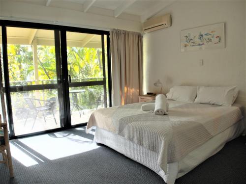 a bedroom with a bed and a large window at Le Court Villas in Noosa Heads