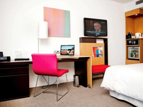 a hotel room with a desk with a computer and a bed at Novotel Warszawa Airport in Warsaw