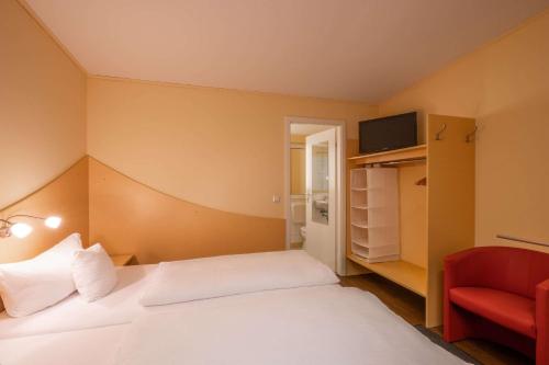 a hotel room with a bed and a red chair at Hotel Lüneburg Süd in Melbeck