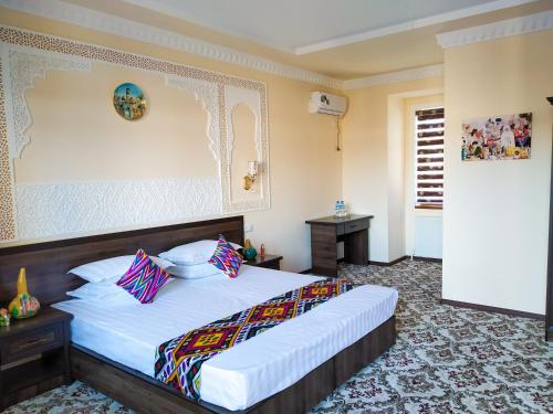 ein Schlafzimmer mit einem großen Bett mit weißer Bettwäsche und bunten Kissen in der Unterkunft Hotel Shams in Buxoro