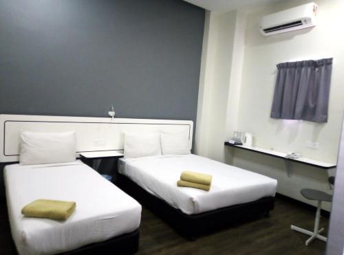 a hotel room with two beds with yellow pillows at NueVo Boutique Hotel, Kota Kemuning, Shah Alam in Shah Alam