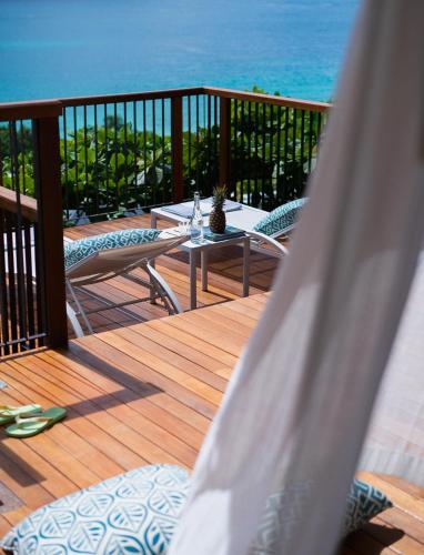 a wooden deck with a table and chairs and the ocean at Raffles Seychelles in Baie Sainte Anne