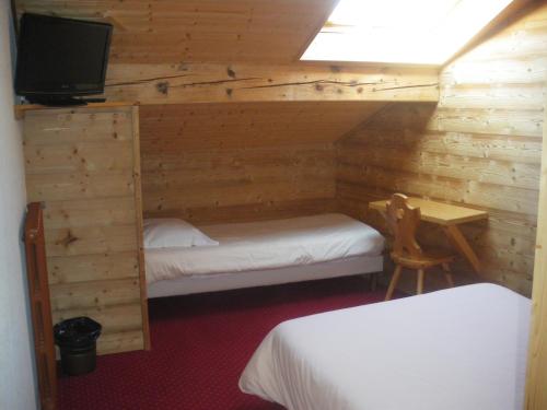 a room with two beds and a desk and a tv at Hotel Le Grand Tetras in Morzine