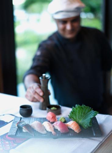 a man sitting at a table with a plate of sushi at Raffles Seychelles in Baie Sainte Anne