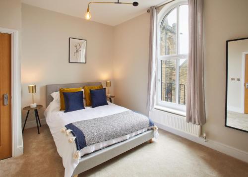 a bedroom with a bed with blue pillows and a window at Host & Stay - Artsbank Apartment in Saltburn-by-the-Sea