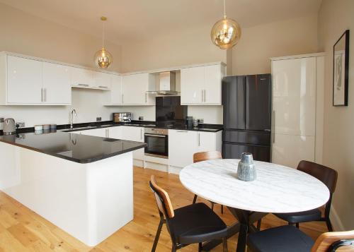 a kitchen with white cabinets and a table with chairs at Host & Stay - Artsbank Apartment in Saltburn-by-the-Sea