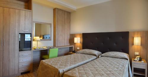 una camera d'albergo con letto e TV di Hotel Rossini a Pesaro