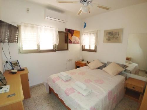 sypialnia z łóżkiem, biurkiem i oknami w obiekcie Carmela House w mieście Arad