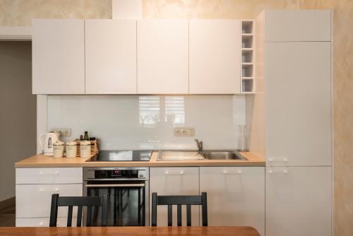 una cucina con mobili bianchi, tavolo e sedie di M terrace a Kaunas