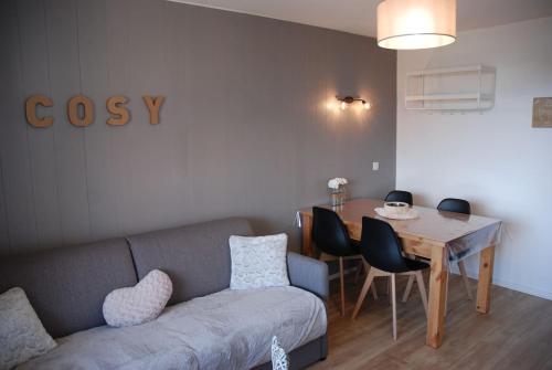 sala de estar con sofá y mesa con sillas en Charmant studio cabine COSY à 100 m des pistes en Chamrousse