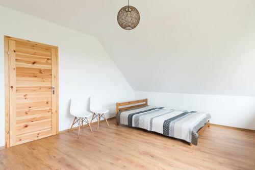 sypialnia z łóżkiem, 2 krzesłami i drzwiami w obiekcie Apartament Lutowiska w mieście Lutowiska