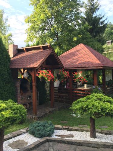 a wooden gazebo in a garden with red flowers at Domeniul Horj Apartament Moisei in Moisei
