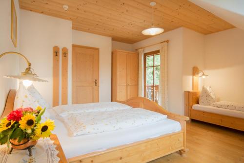 a bedroom with a bed and a vase of flowers on a table at Peterer Hof in Rasùn di Sotto