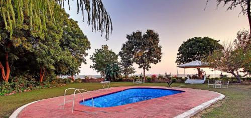 una piscina en medio de un patio con árboles en Bhadrawati - A Riverside Safari Lodge Ranthambore, en Sawāi Mādhopur