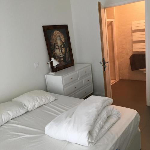 une chambre avec un lit blanc avec un tableau sur le mur dans l'établissement Residence vue de reve - 1 ere ligne de plage, à Arcachon